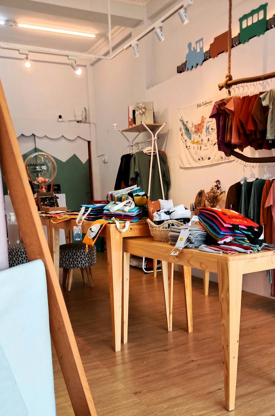 Boutique pour enfants avec des tables en bois présentant des vêtements pliés et des accessoires.
