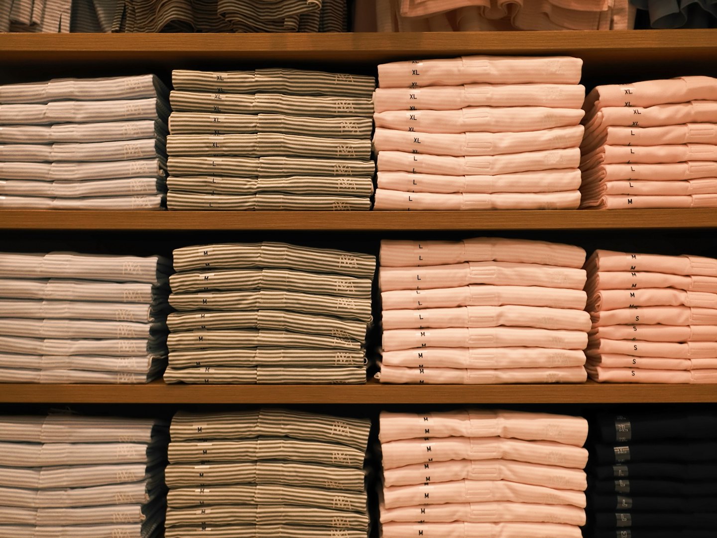 T-shirts pliés proprement empilés sur des étagères en bois.